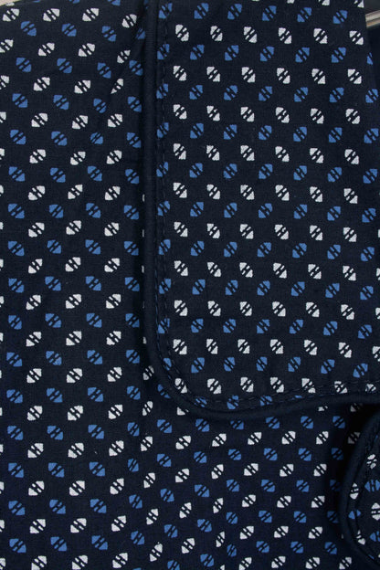 Close-up van donkerblauwe pyjamastof met wit en lichtblauw geometrisch patroon, zichtbare knoopsluiting.
