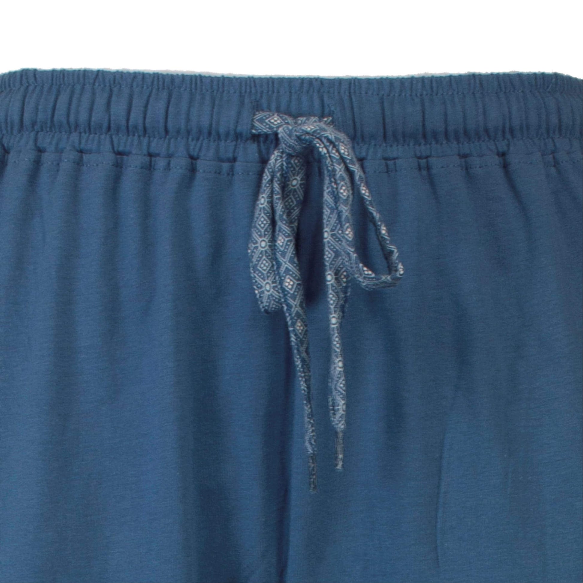 Close-up van een petrolblauwe pyjamabroek met elastische tailleband en een geprint koordje met geometrisch patroon.