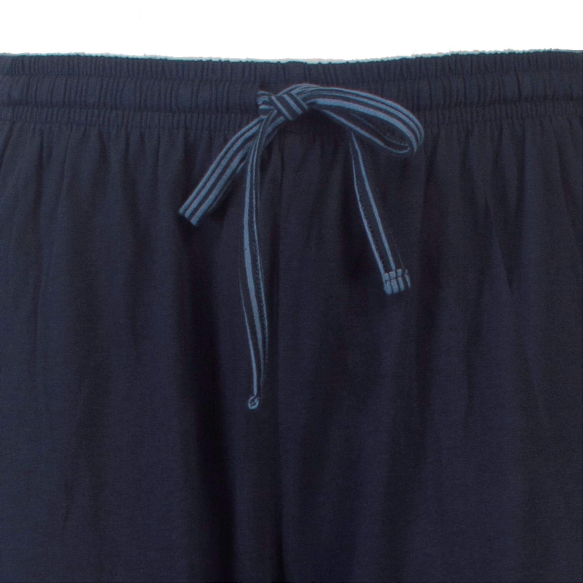 Close-up van een petrol blauwe pyjamabroek met een gestreept trekkoord in de taille