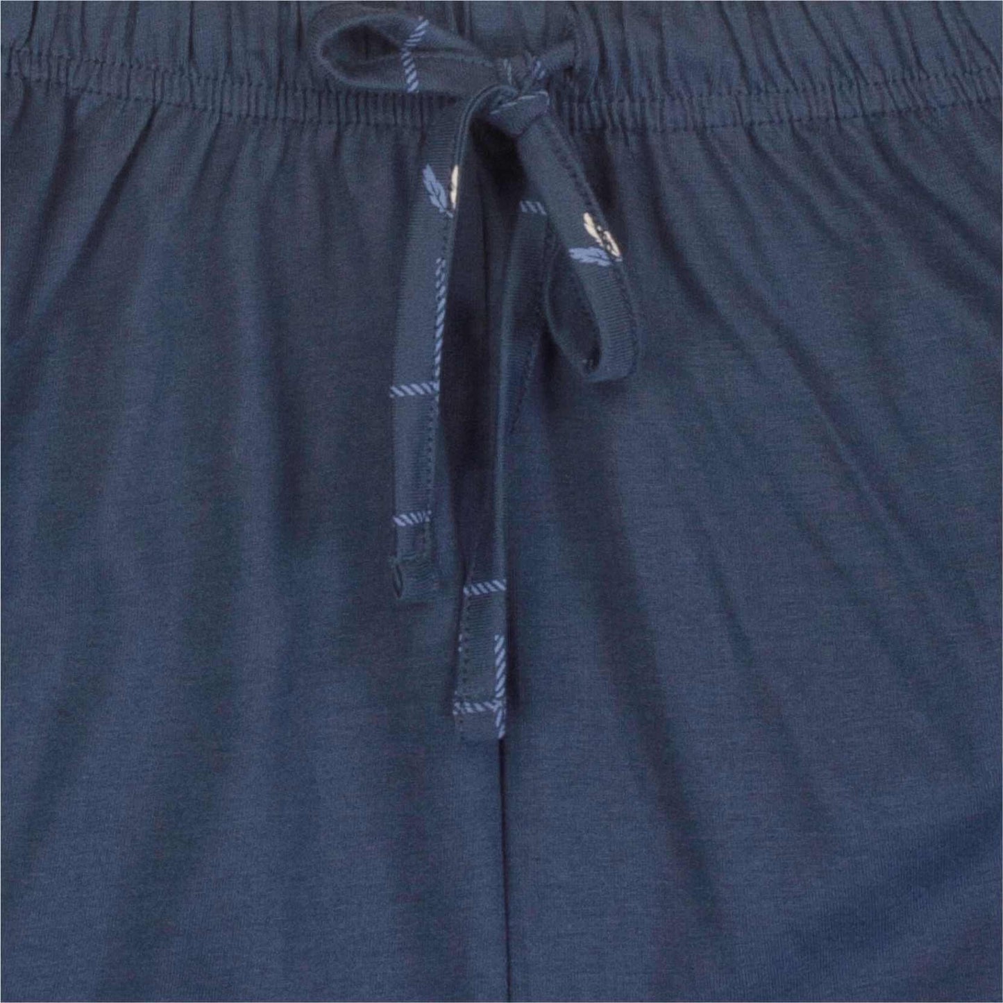 Close-up van een jeansblauw pyjama-broek met elastische band en aantrekkoord met gestreepte uiteinden