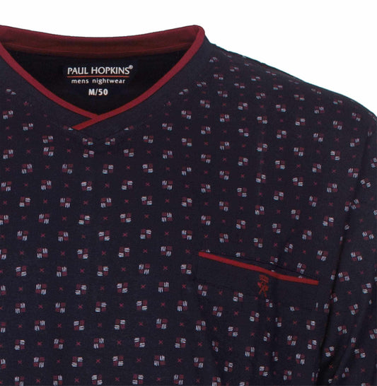 Donkerblauwe pyjama top met V-hals, rode bies en klein patroon van witte en rode stippen en kruisjes.