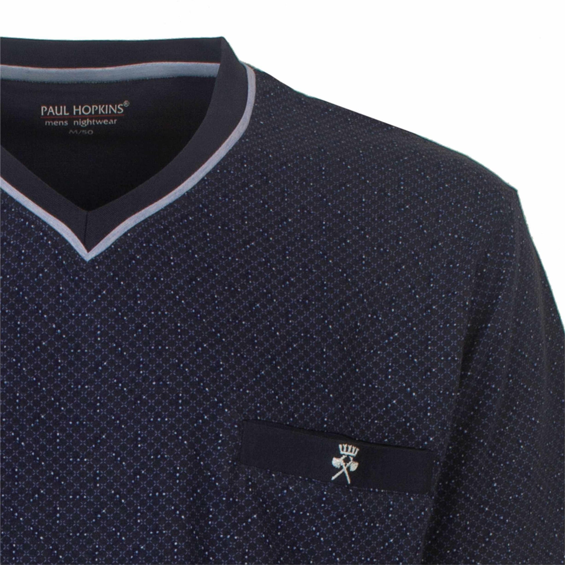Close-up van een donkerblauwe pyjama top met V-hals en subtiel stippenpatroon, Paul Hopkins logo zichtbaar.