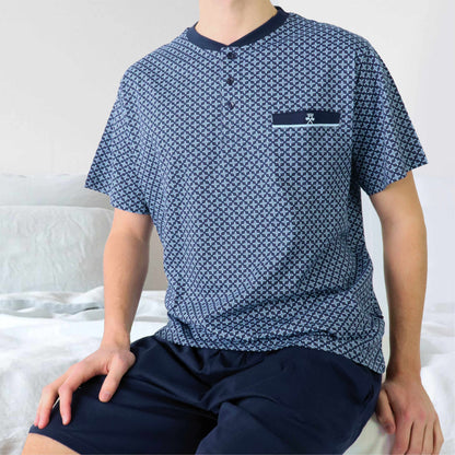 Donkerblauwe heren shortama met polo sluiting, geometrisch patroon en korte mouwen, zittend op bed.