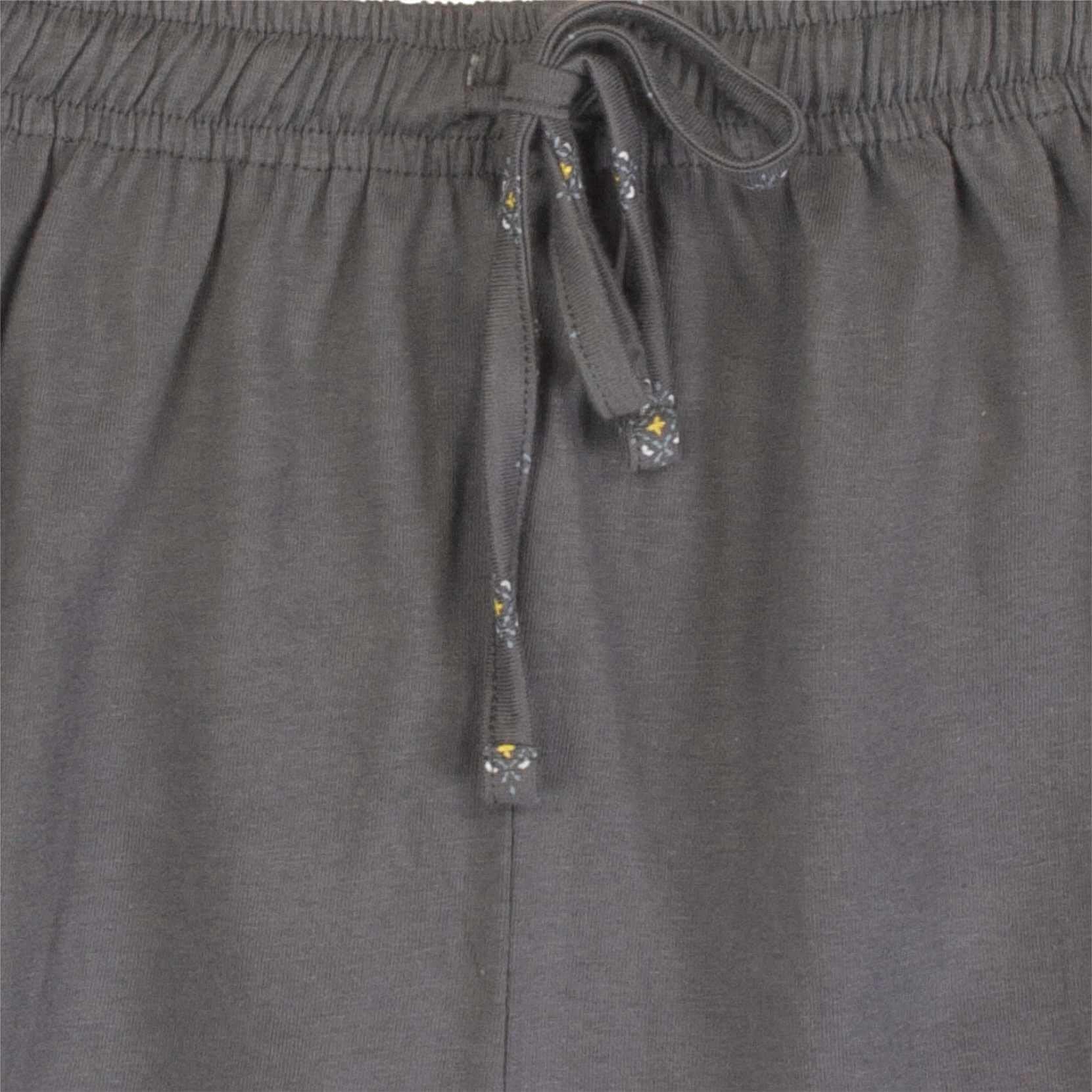 Close-up van de taille van een grijze pyjama broek met een elastische band en een koord met decoratieve uiteinden.