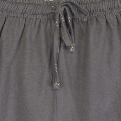 Close-up van de taille van een grijze pyjama broek met een elastische band en een koord met decoratieve uiteinden.