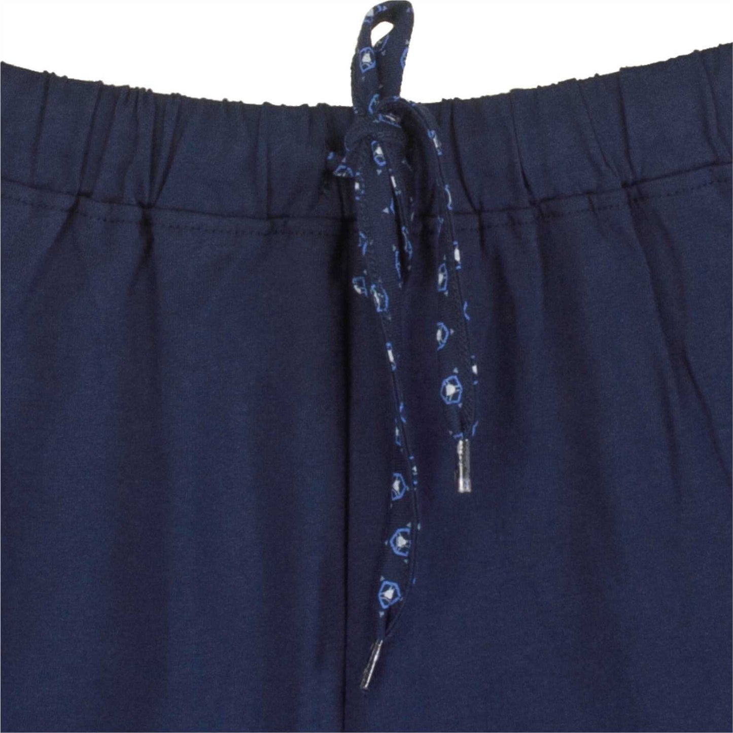 Close-up van de tailleband van een blauwe pyjama met elastiek en een gedessineerd koord met metalen uiteinden.