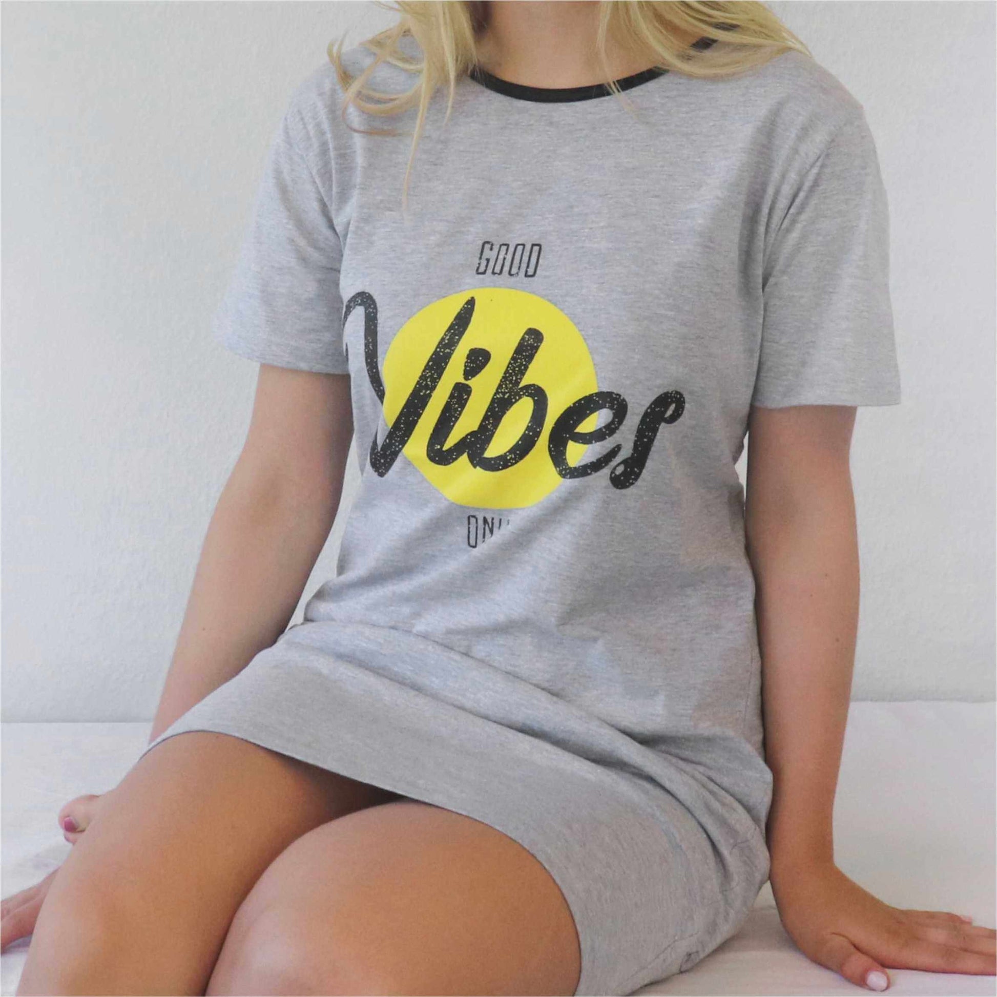 Grijze dames bigshirt met 'Good Vibes Only' opdruk, gele cirkel en zwarte letters, gedragen door blonde vrouw