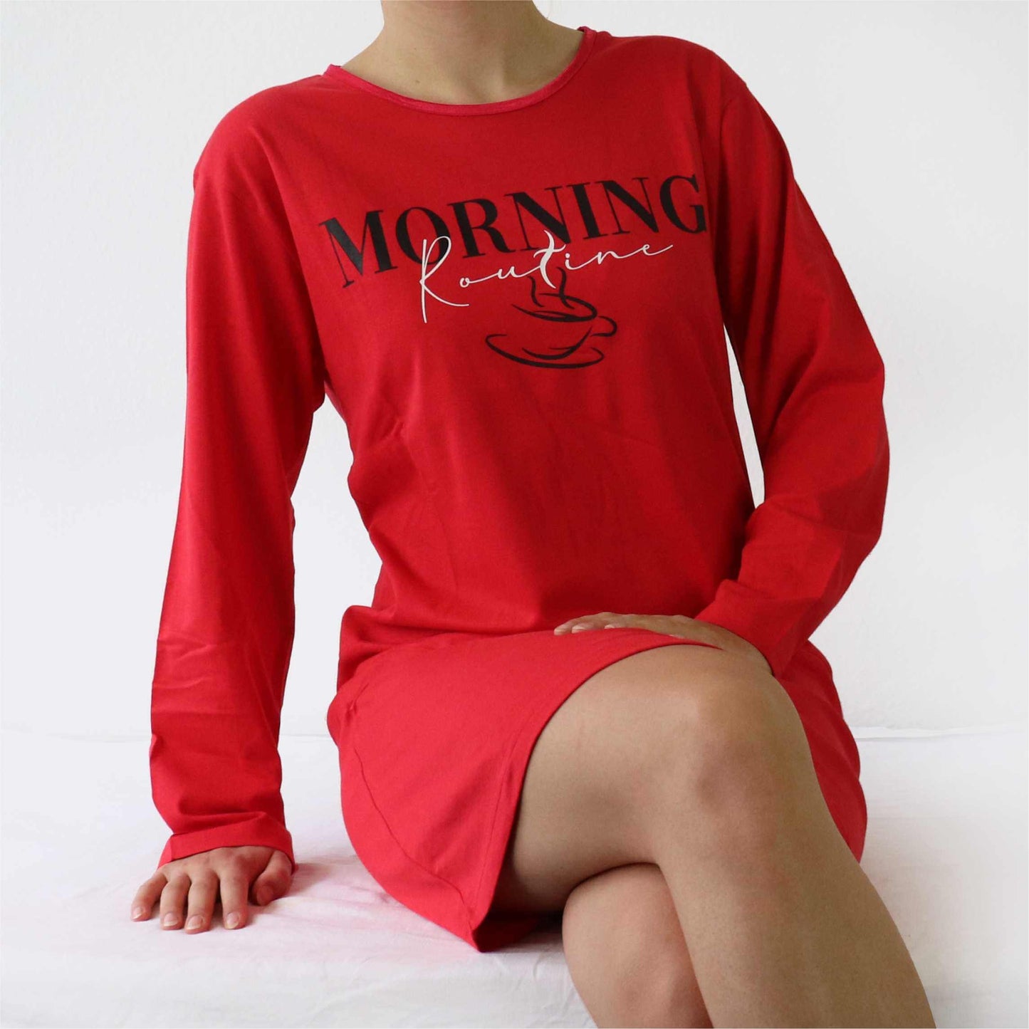 Rood nachthemd met lange mouwen en 'Morning Routine' opdruk, gedragen door een zittende vrouw