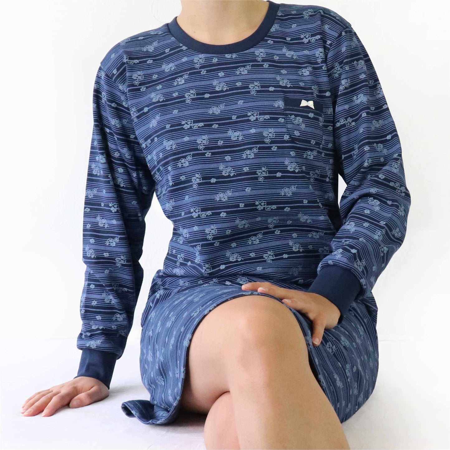 Donkerblauw fleece nachthemd met bloemetjespatroon, lange mouwen en ronde hals, gedragen door een zittende persoon.
