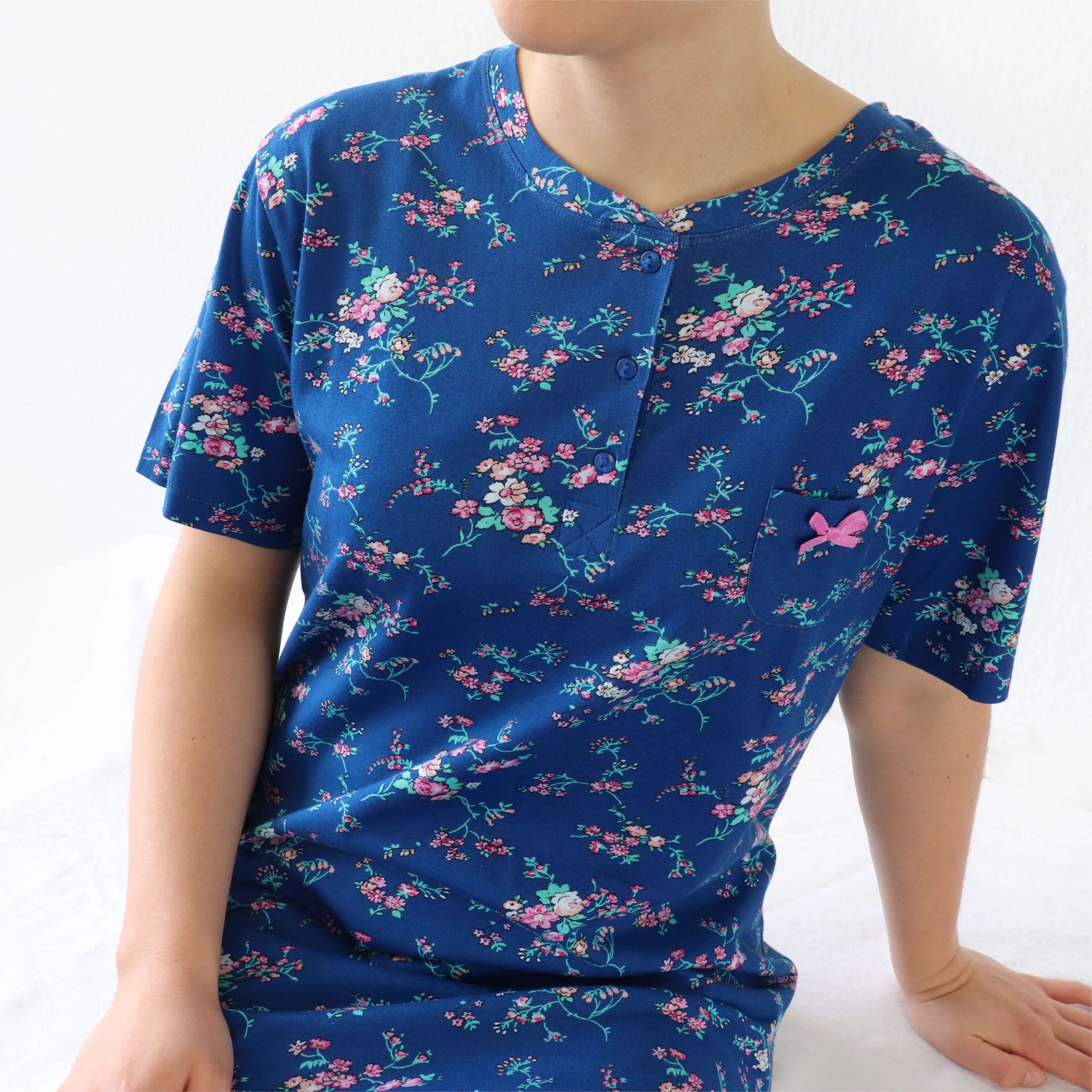 Blauw nachthemd met korte mouwen, versierd met een roze bloemenpatroon en een strikje op de borst.