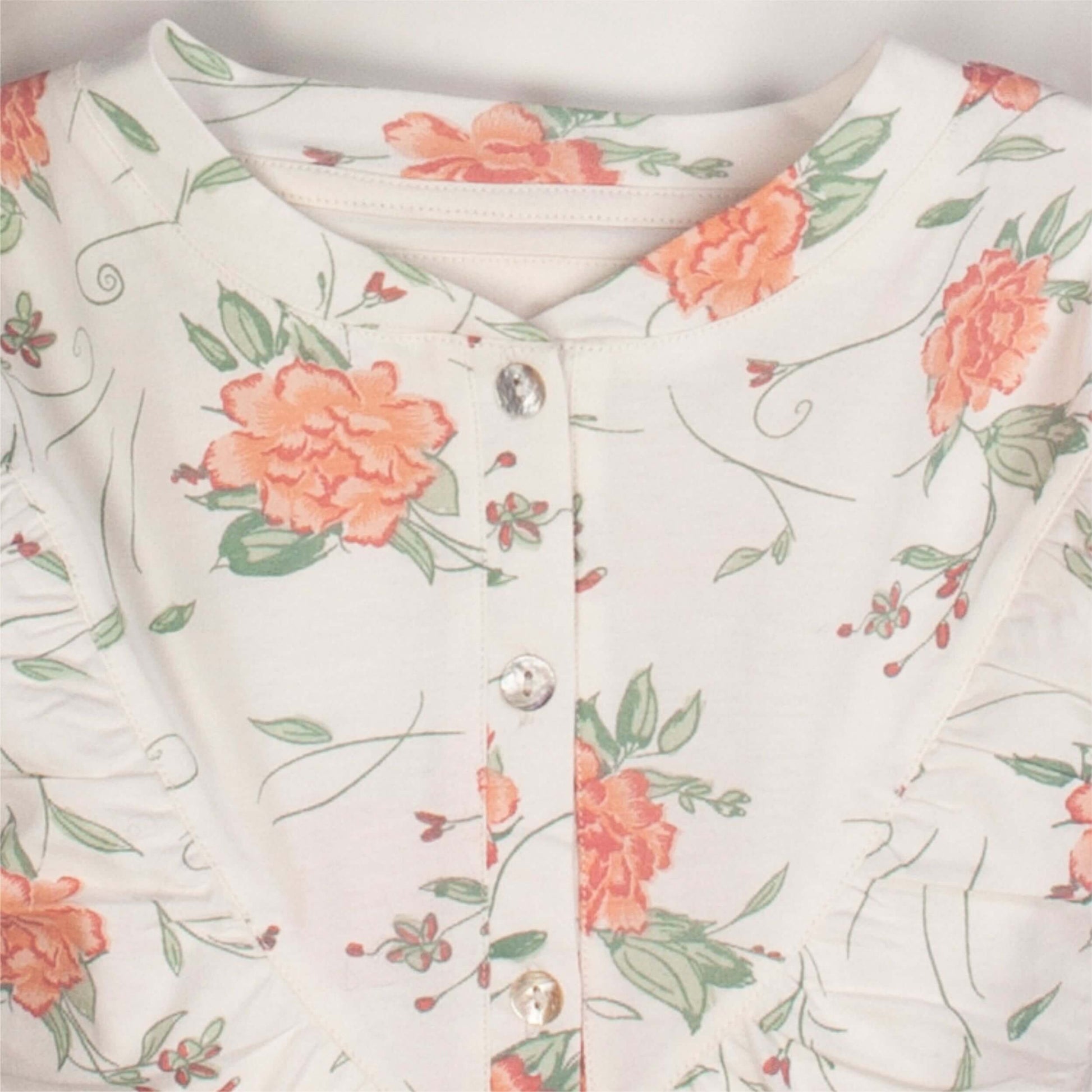 Beige nachthemd met korte mouwen, versierd met koraalkleurige bloemen en groene bladeren panoopsluiting zichtbaar.