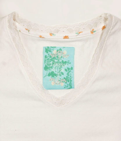 Wit dames nachthemd met V-hals, kanten boord en kleine bloemmotieven. Blauw label met groen plantenpatroon.
