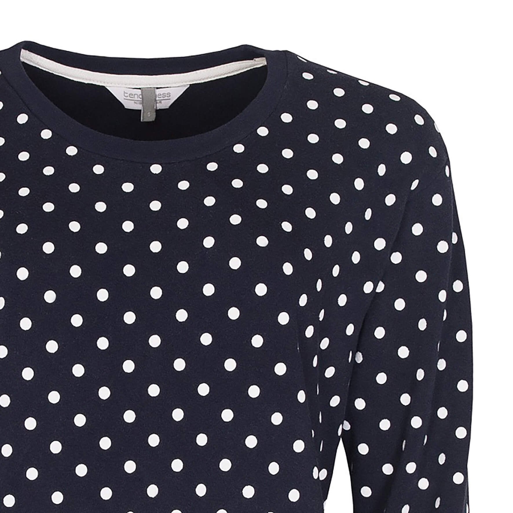 Donkerblauwe pyjama top met witte stippen, ronde hals en lange mouwen. Gedeeltelijk zichtbaar.