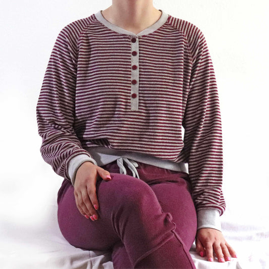 Gestreepte bordeauxrode pyjama top met grijze accenten, gedragen met bijpassende bordeauxrode broek.