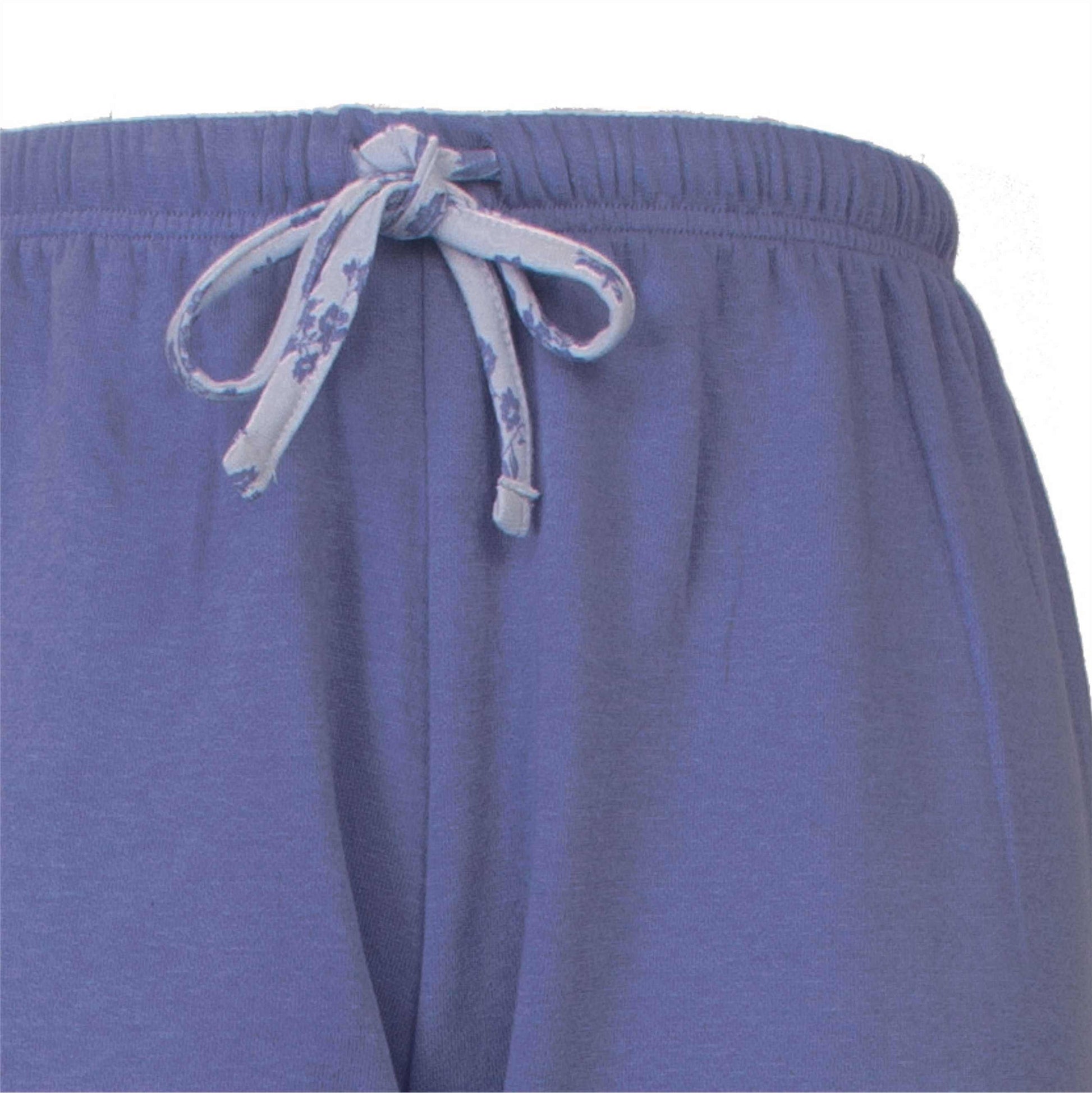 Close-up van blauwe fleece pyjamabroek met een gebloemde strikkoord aan de taille.