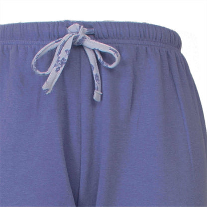 Close-up van blauwe fleece pyjamabroek met een gebloemde strikkoord aan de taille.