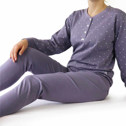 Lila fleece pyjama met witte stippen, lange mouwen en knopen aan de hals, gedragen door een zittend model.