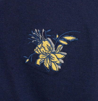 Donkerblauwe stof met geborduurde gele bloem, detail van een pyjama top