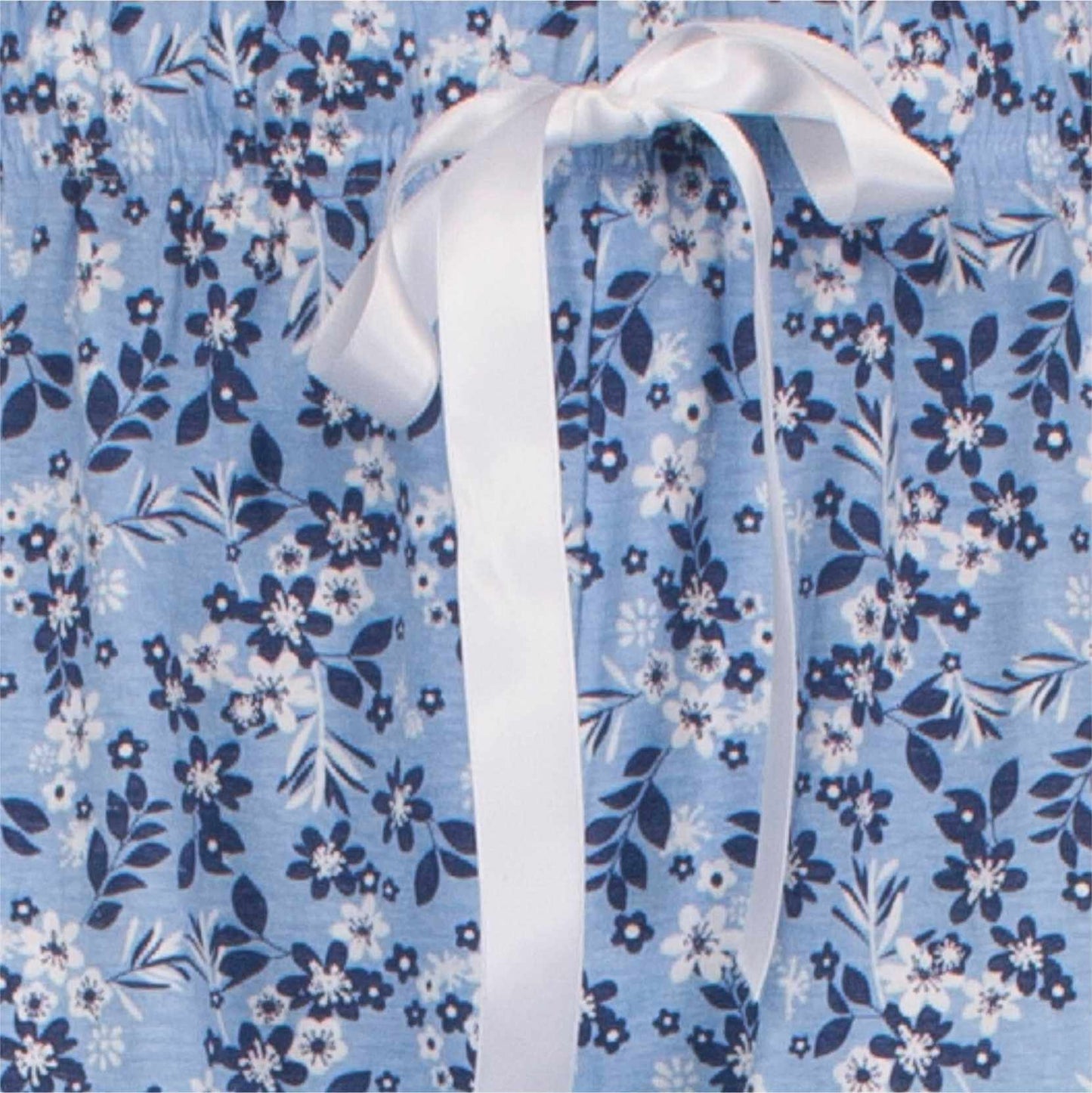 Indigo blauwe pyjama met wit bloemenpatroon en een witte strik in het midden van de afbeelding.