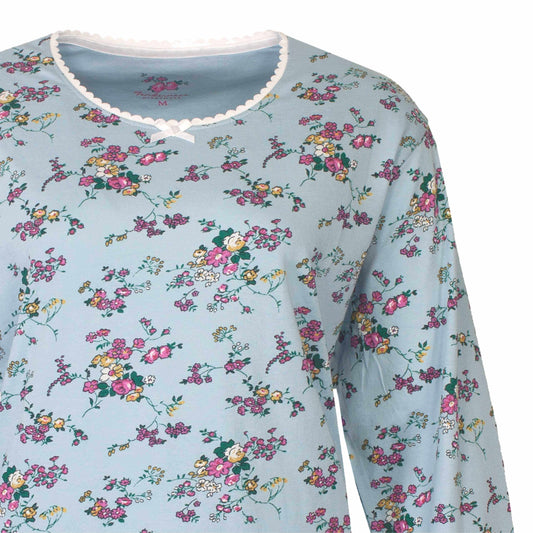 Mintblauwe pyjama met lange mouwen, versierd met kleine roze en gele bloemetjes, afgewerkt met wit kant aan de hals.