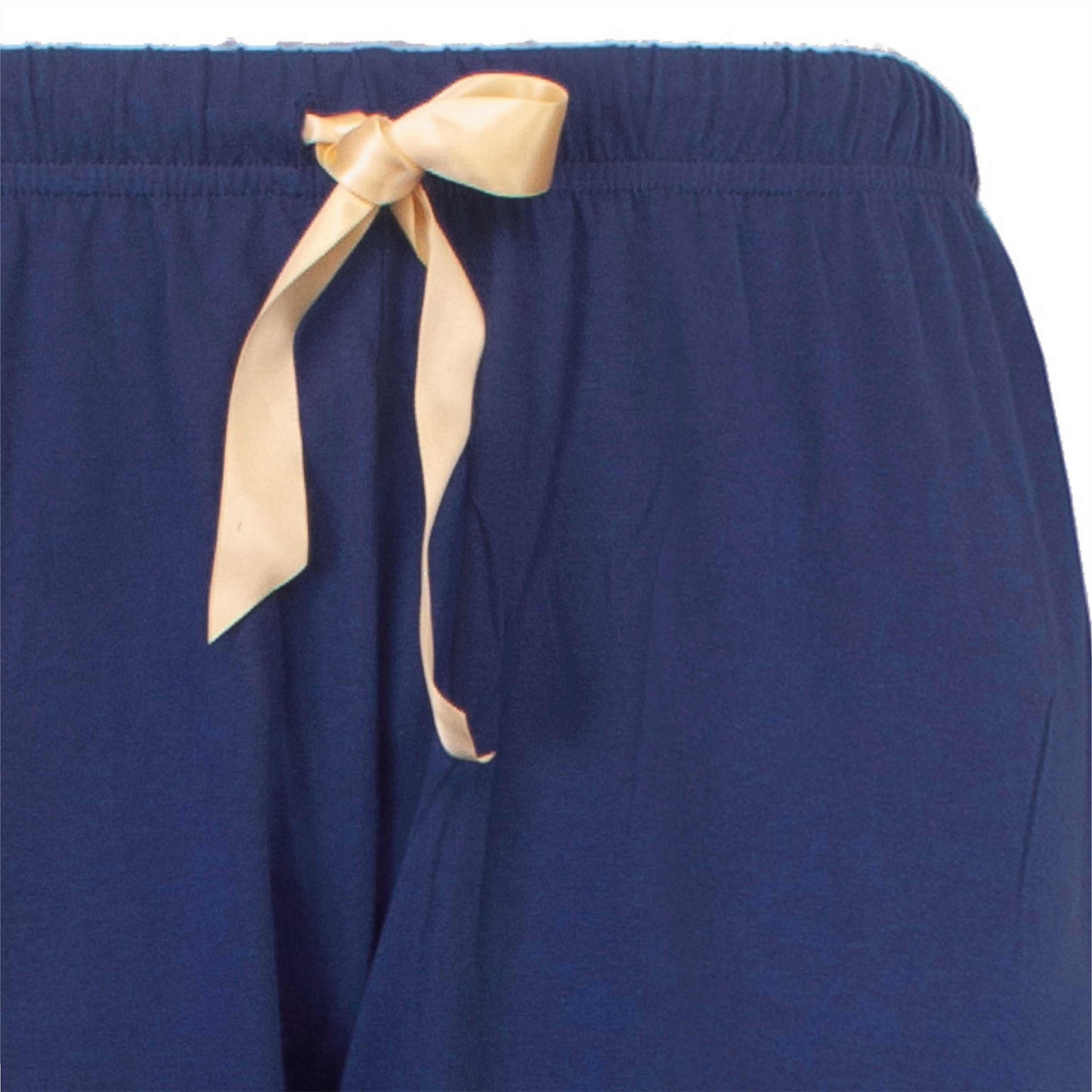 Detailopname van een blauwe pyjama broek met een beige lint als tailleband, elastische taille zichtbaar.