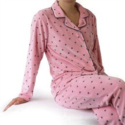 Roze velours pyjama met lange mouwen en broek, bedrukt met kleine donkere stippen, zittend model getoond
