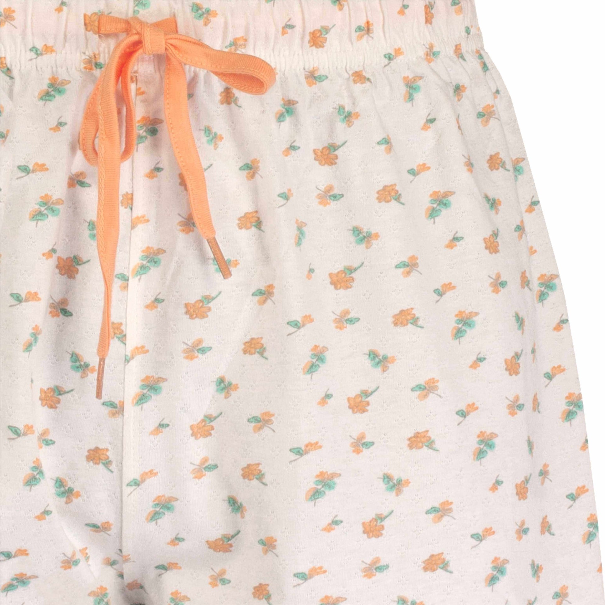 Witte shortama met oranje en groene bloemenprint, oranje strik bij de taille, mouwloos ontwerp